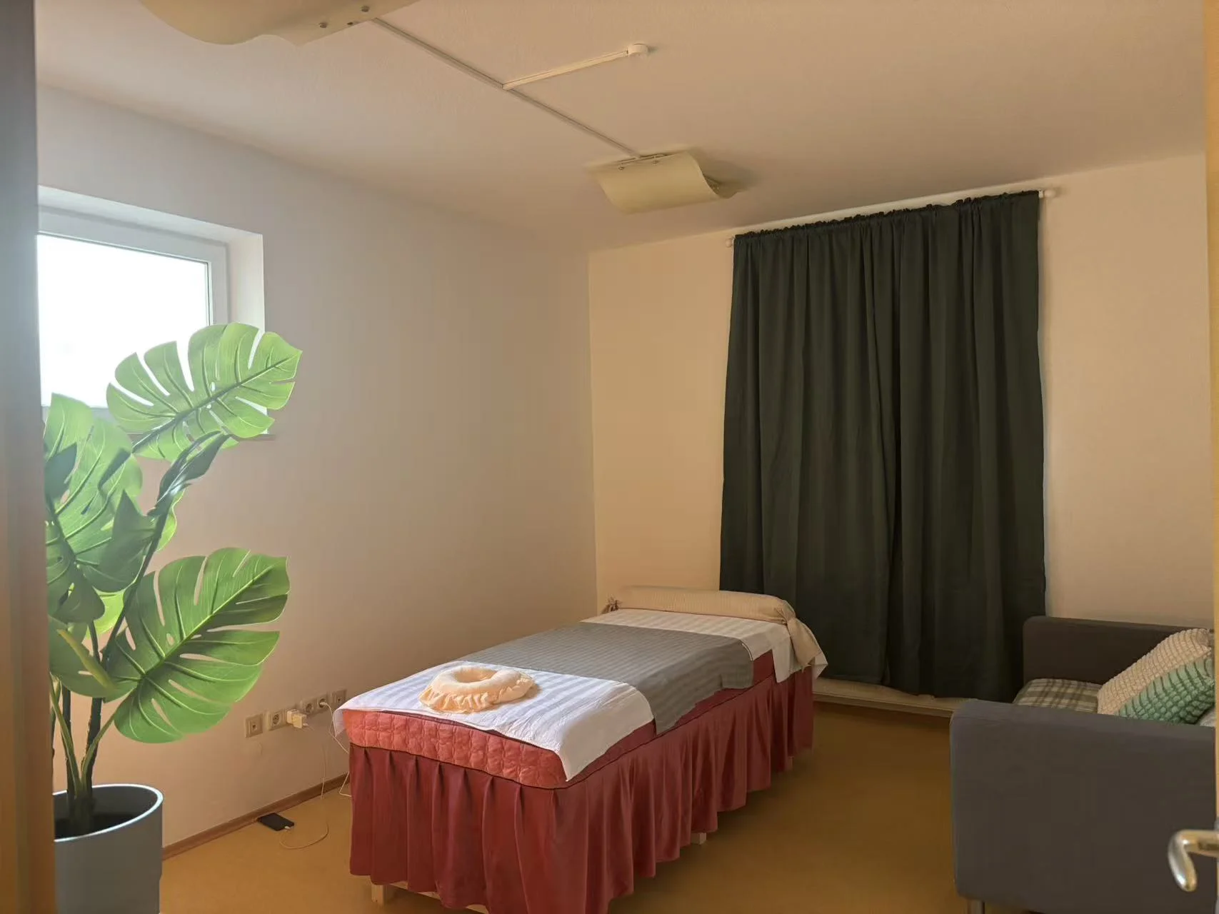 Empty room with white walls, dark wood flooring, and a decorative modern spiral lamp on a small cabinet. Large window and door provide natural light.