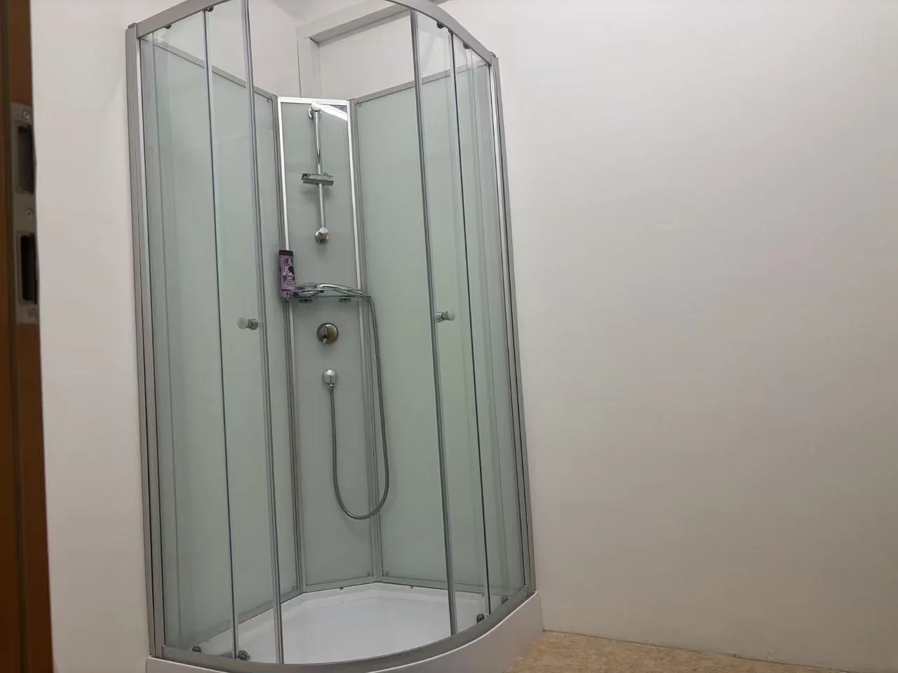 Entrance hallway with white walls, dark wood flooring, white doors, and a wall-mounted cabinet. Warning sign for steps visible on the floor.